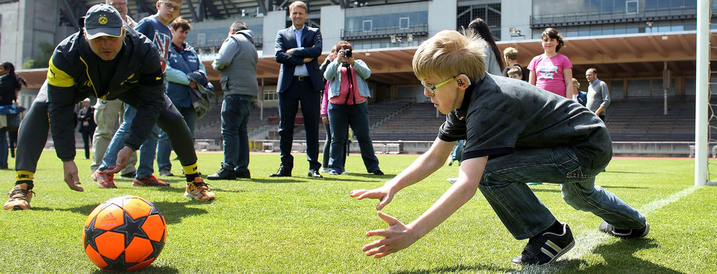 Ein Junge steht im Tor und versucht einen Ball zu fangen.