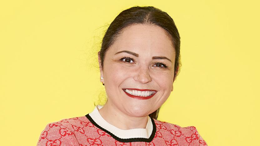 Eine Frau steht mit verschränkten Armen und lächelt