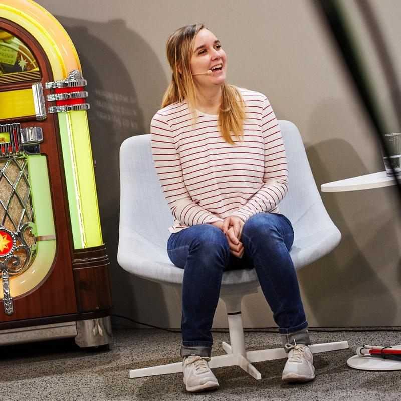 Fabie sitzt auf einem Stuhl neben einer Jukebox.