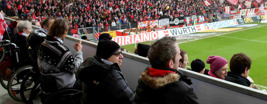 Mehrere Rollstuhlfahrer im Stadion schauen ein Fußballspiel
