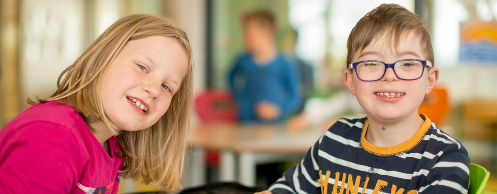 Zwei Kinder lächeln in die Kamera.