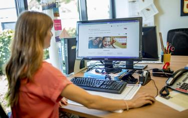Eine Frau sitzt vor dem Computer. Auf dem Bildschirm ist die Starteseite des Aktion Mensch-Familienratgebers zu sehen.