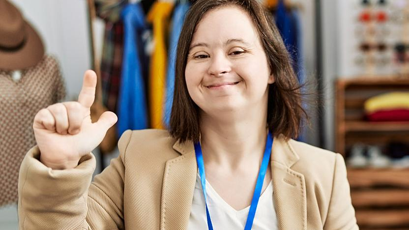 Junge Verkäuferin mit Down-Syndrom in Kleidergeschäft