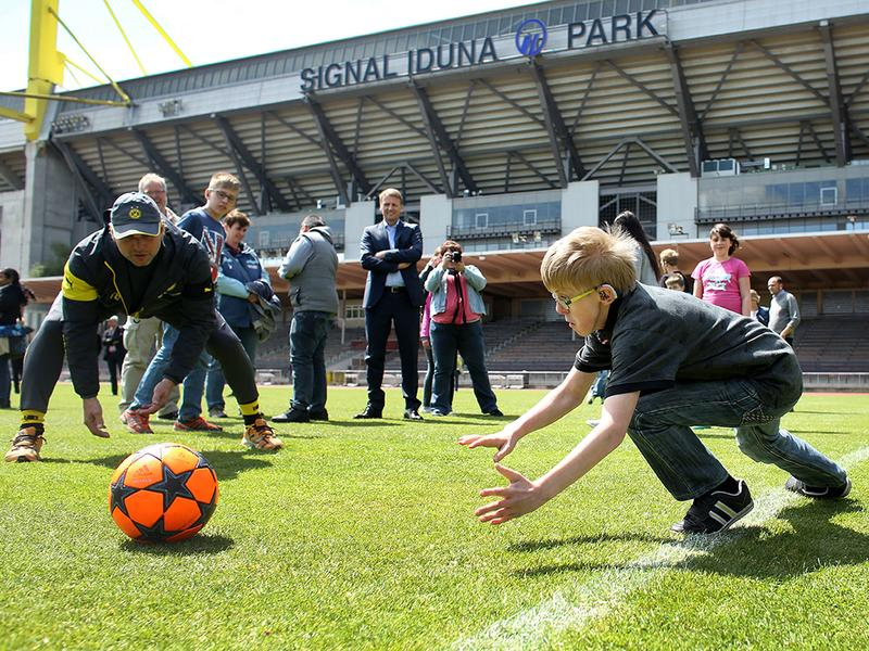Eine Gruppe Erwachsener und Kinder ist in einem Fußballstadion und spielt Fußball. 