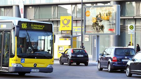 Ein Bus fährt auf eine Haltestelle zu. Ihm entgegen kommen mehrere Autos.