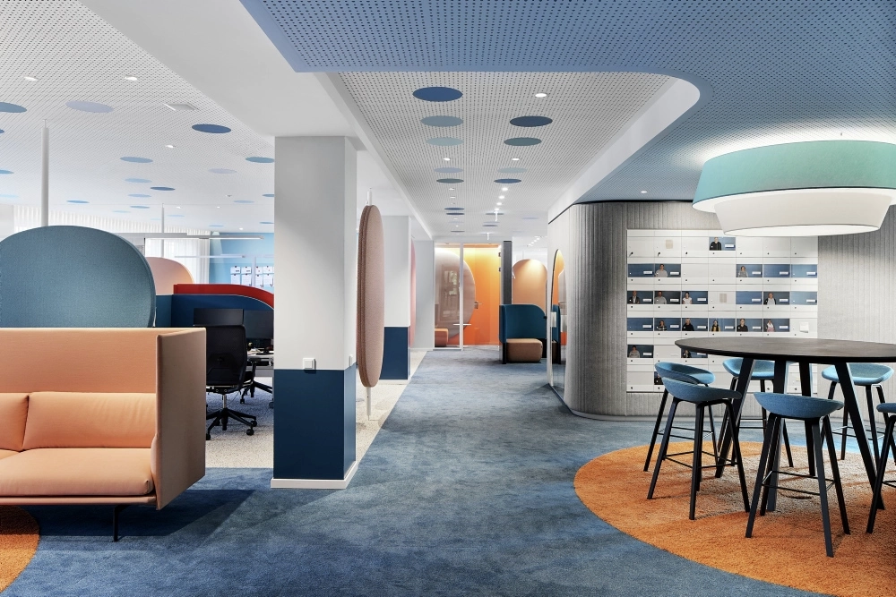 Ein Bild der Büroräume der Aktion Mensch mit blauem Teppichboden und einer Sitzecke.