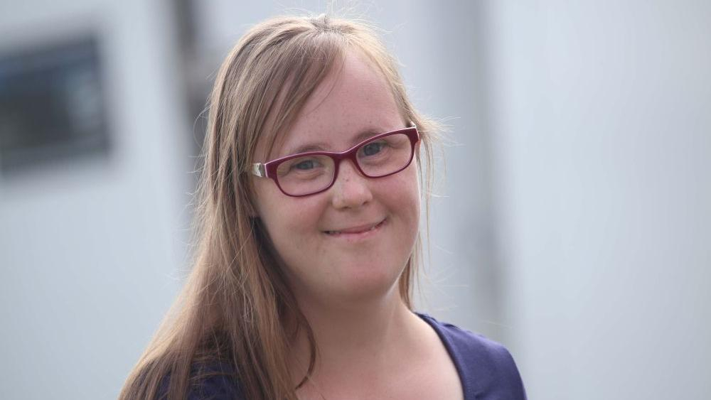 Porträt von Carina Kühne: eine junge Frau mit langen blonden Haaren und Brille.