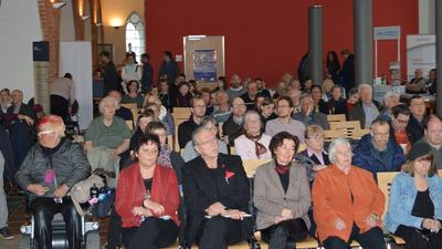 viele menschen sitzen im publikum und hören zu