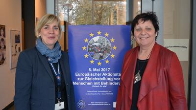 zwei Frauen stehen vor einem Plakat