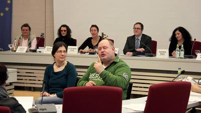 zwei Gebärdensprachdolmetscher sitzen vor 5 Teilnehmern der Auftaktveranstaltung