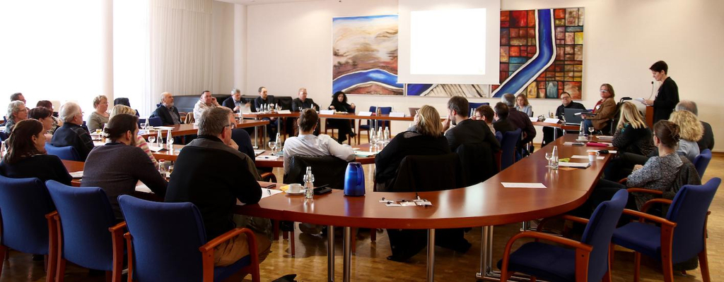 Viele Menschen sitzen an einem Konferenztisch.