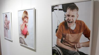 Kunstausstellung mit Leinwändenauf einer ist ein Junge im Rollstuhl zu sehen, der sich freut
