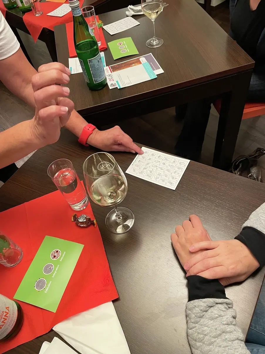 Eine Hand macht eine Gebärde, eine andere Hand zeigt auf ein Gebädernsprach-Alphabet