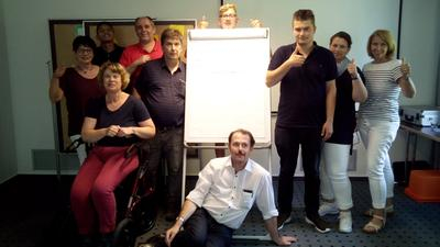 Eine Gruppe Menschen steht um ein Flipchart herumgruppiert