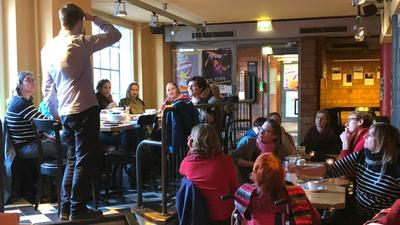 Ein Mann spricht vor einem Publikum in einer Kneipe