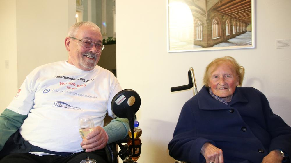 zwei alte menschen sitzen im rollstuhl und lächeln