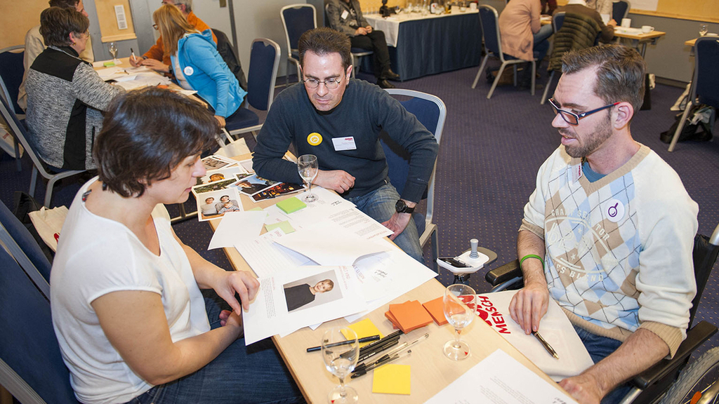 Auf der Netzwerktagung in Nürnberg arbeiten vier Teilnehmer an einem Tisch zu einem Workshop-Thema