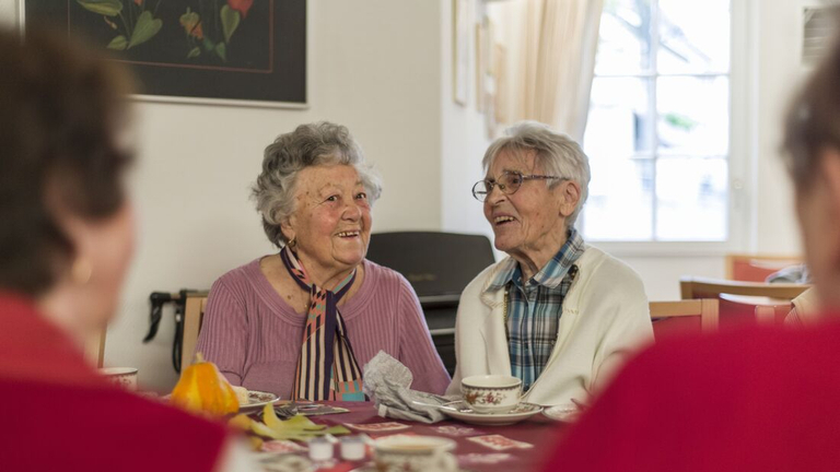 Zwei ältere Frauen unterhalten sich beim Kaffee trinken.
