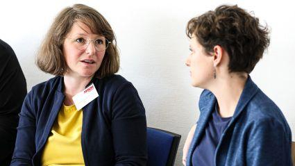Zwei Frauen sitzen nebeneinander und unterhalten sich