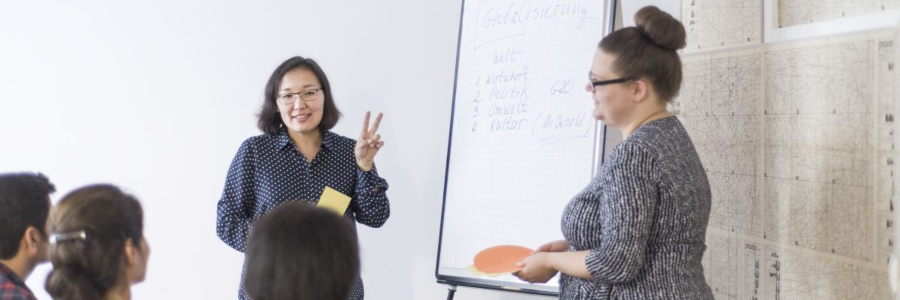 Zwei Frauen präsentieren etwas mit einem Whiteboard.