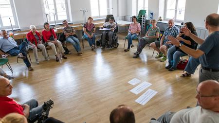 Eine Gruppen von Menschen mit und ohne Behinderung sitzt während eines Workshops im Kreis