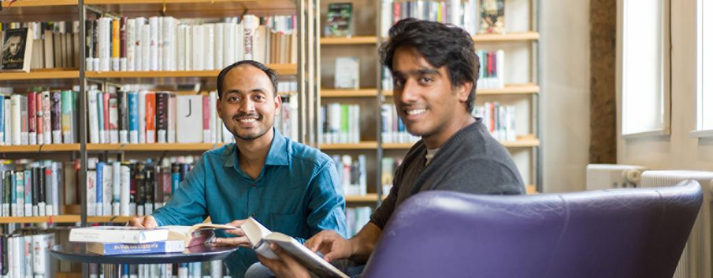 Zwei junge Männer sitzen lesend in einer Bibliothek