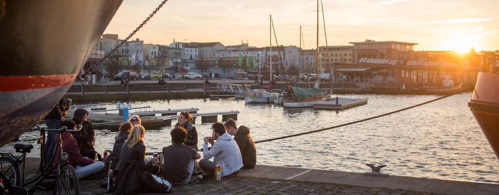 Junge Menschen sitzen am Rostocker Hafen