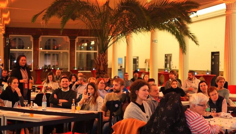 Viele Menschen sitzen in einem Raum und hören zu.