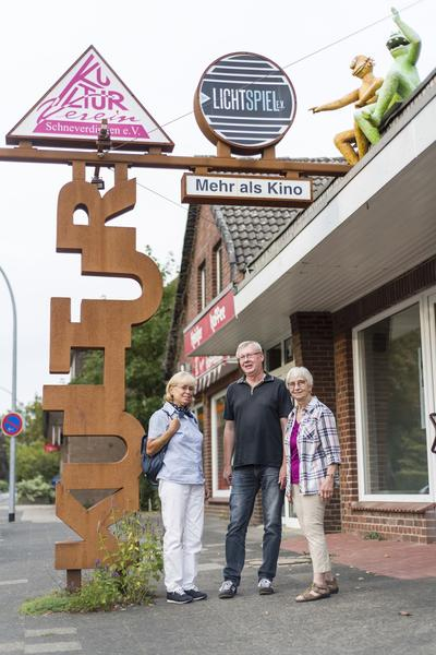 Ein Mann und zwei Frauen stehen vor dem Kino Lichtspiel in Schneverdingen. 