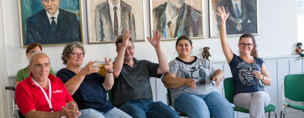 Ein Rollstuhlfahrer sitzt zusammen mit anderen in einem Halbkreis 