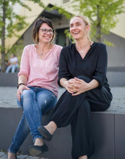 zwei Frauen sitzen auf einer Mauer