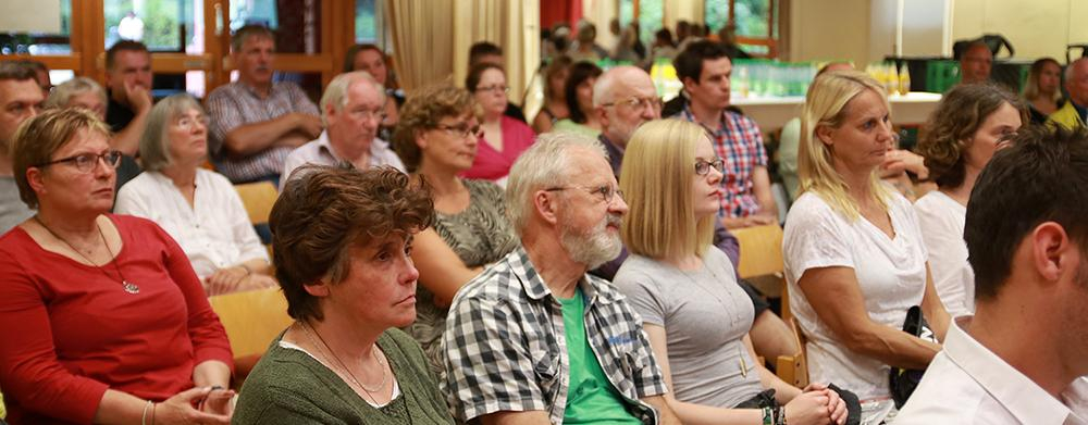 Ein Blick ins Publikum: mehrere Frauen und Männer hören interessiert zu