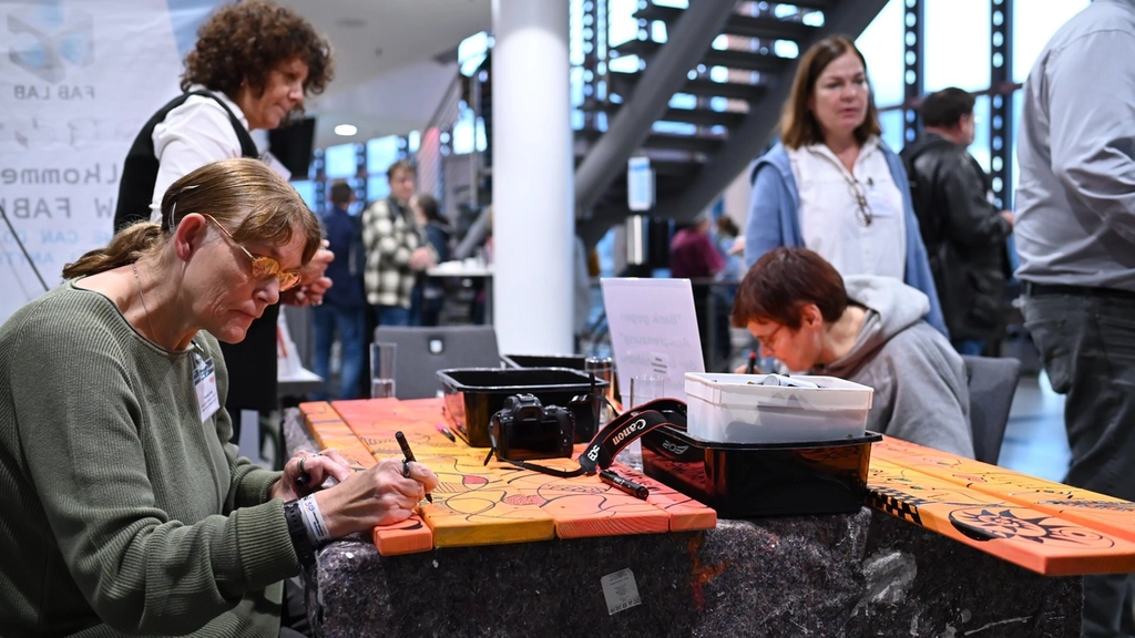 Zwei Frauen bemalen Teile einer Bank beim Kongress 2024 in Erfurt