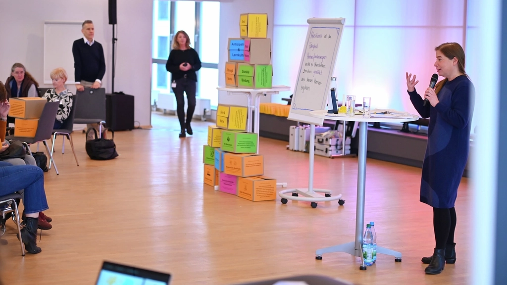 Workshopszene: Eine Frau mit Mikrofon spricht zu Teilnehmer*innen