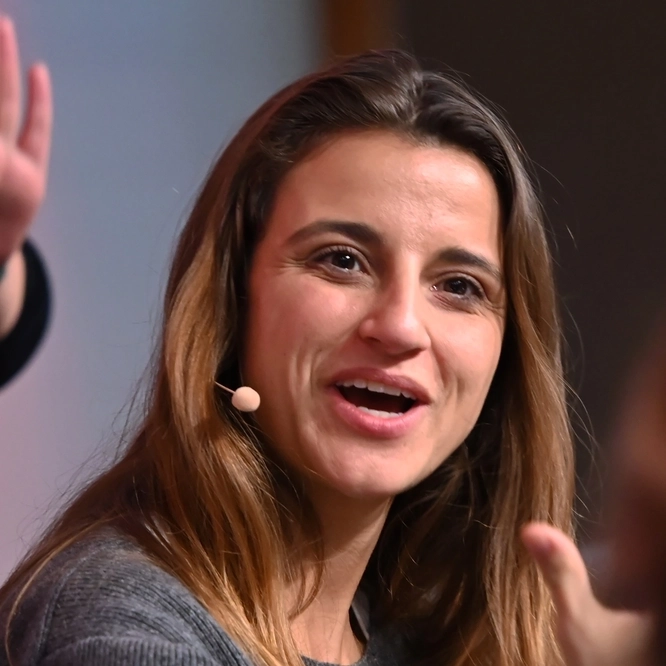 Pauline Fröhlich diskutiert auf einem Podium, im Hintergrund steht eine Gebärdensprachdolmetscherin