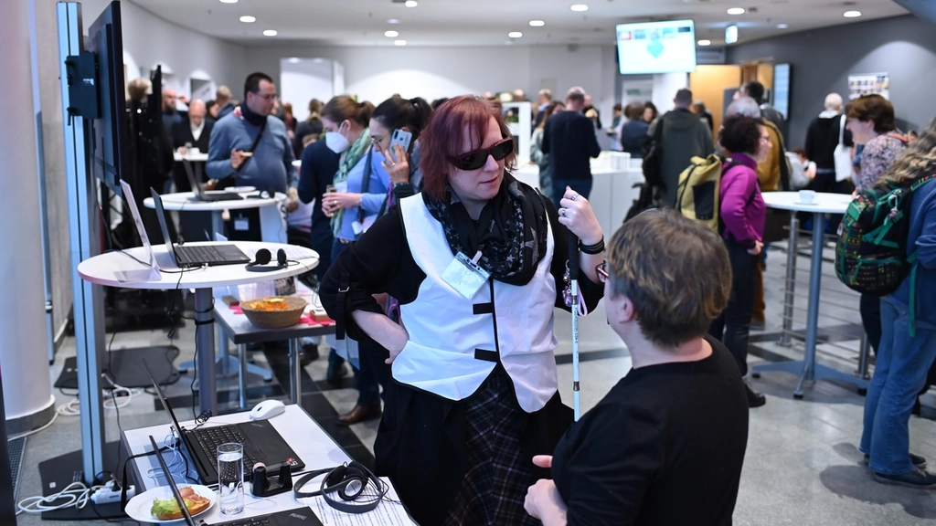 Mehrere Personen, darunter eine blinde Frau mit Langstock, unterhalten sich während einer Kongress-Pause