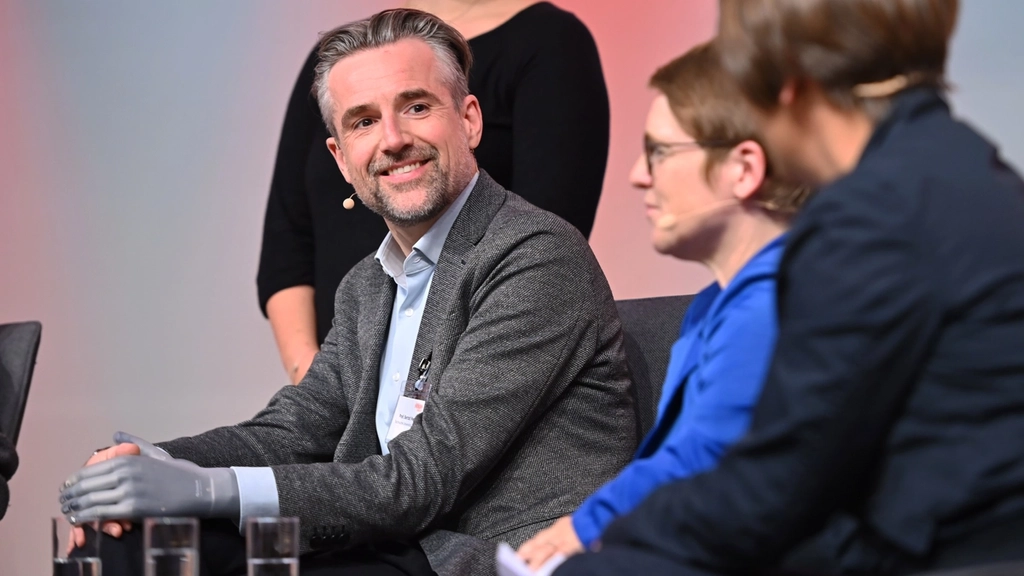 Bild einer Podiumsdiskussion mit Bertolt Meyer, der eine Handprothese trägt.