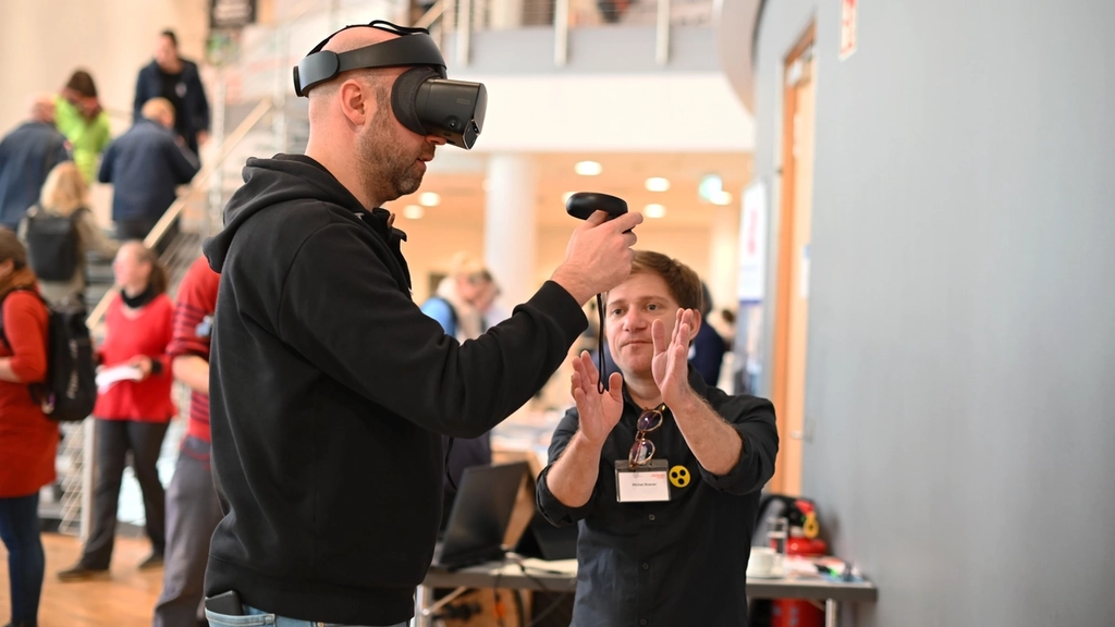 Ein Mann trägt beim Kongress 2024 eine VR Brille an einem Infostand