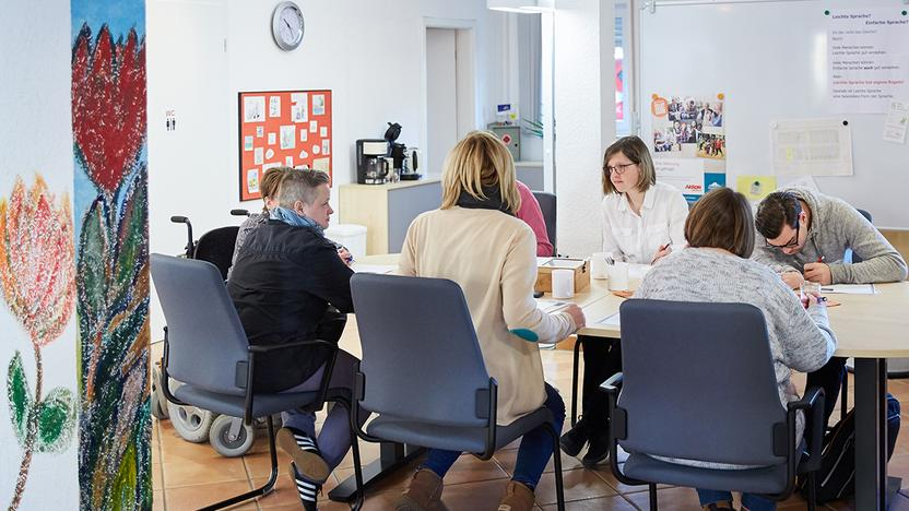 Frauen und Männer sitzen an einem Tisch und arbeiten zusammen