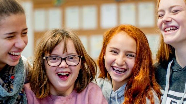 Vier junge Mädchen lachen in die Kamera.