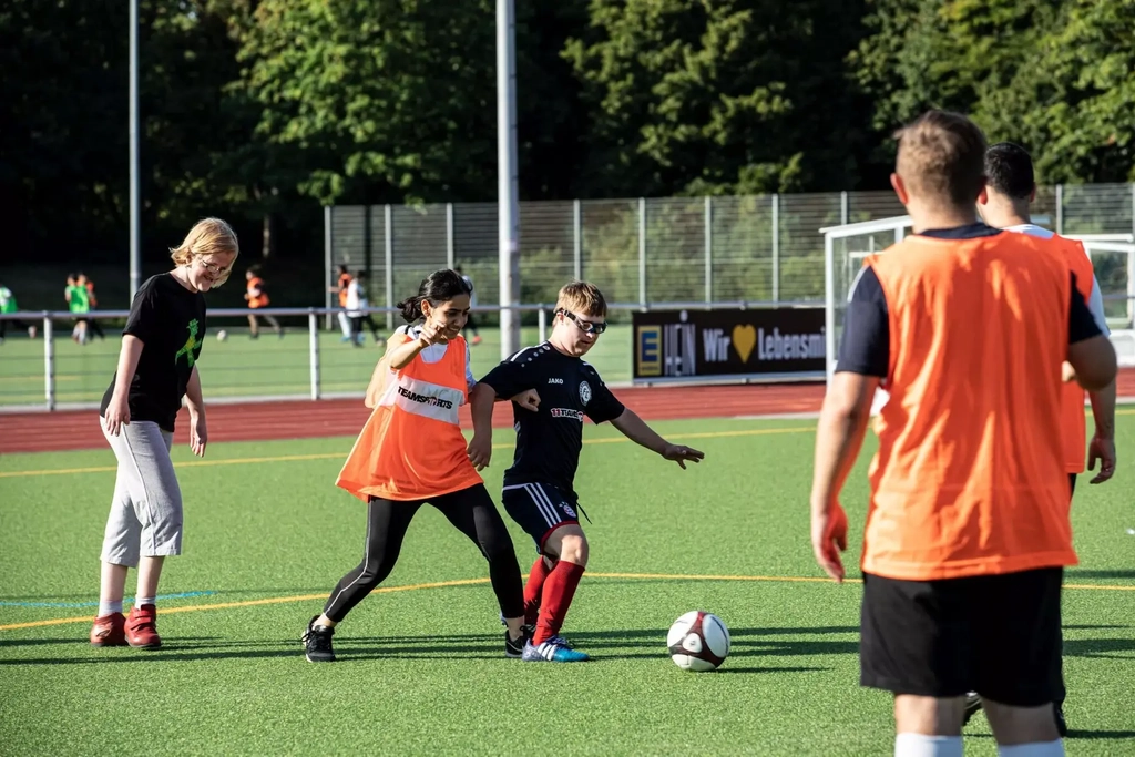 Die Spieler*innen des FC Germania Zündorf kämpfen auf dem Fußballplatz um den Ball.