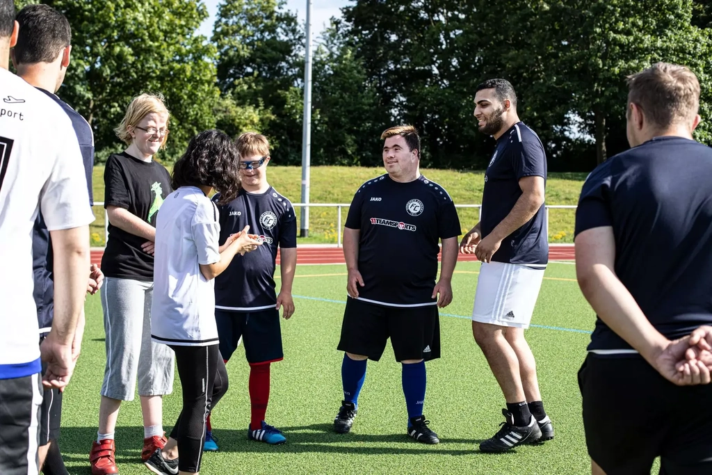 Die Die Mitglieder des FC Germania Zündorf stehen auf dem Fußballplatz und besprechen ihre Taktik.
