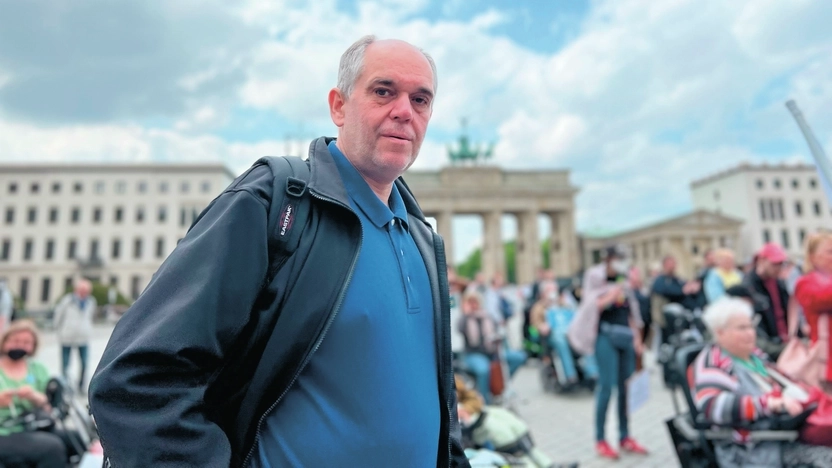 Ottmar Miles-Paul - ein Mann mit kurzen, grauen Haaren - steht vor dem Brandenburger Tor. Im Hintergrund sieht man unscharf weitere Menschen.