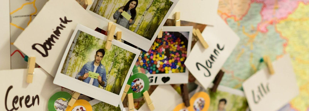 Eine Pinnwand mit Bildern junger Menschen, Namensschildern und bunten Buttons.