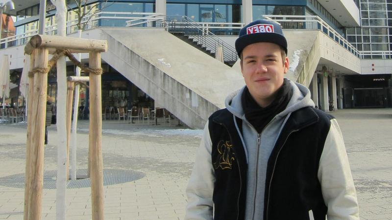 Teenie mit Käppi steht draußen und blickt in die Kamera.