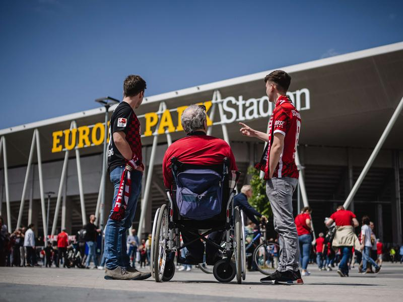 Vor einem Fußballstadion mit dem Schriftzug
