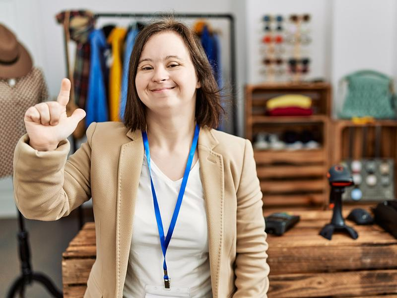 Junge Verkäuferin mit Down-Syndrom in Kleidergeschäft