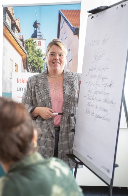 Eine Frau steht an einem Flipchart und erklärt etwas