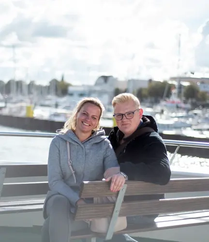 Ein Mann und eine Frau sitzen am Hafen auf einer Bank.