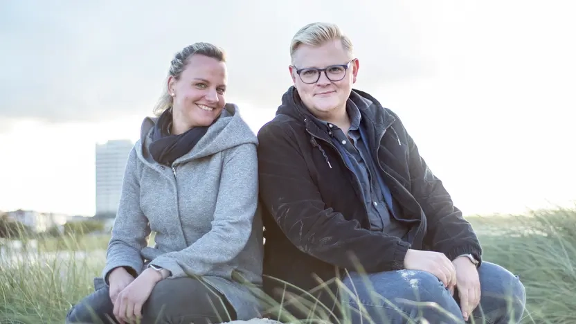 Anja Schulz und Erik Ortlieb sitzen auf einer Düne im Sand